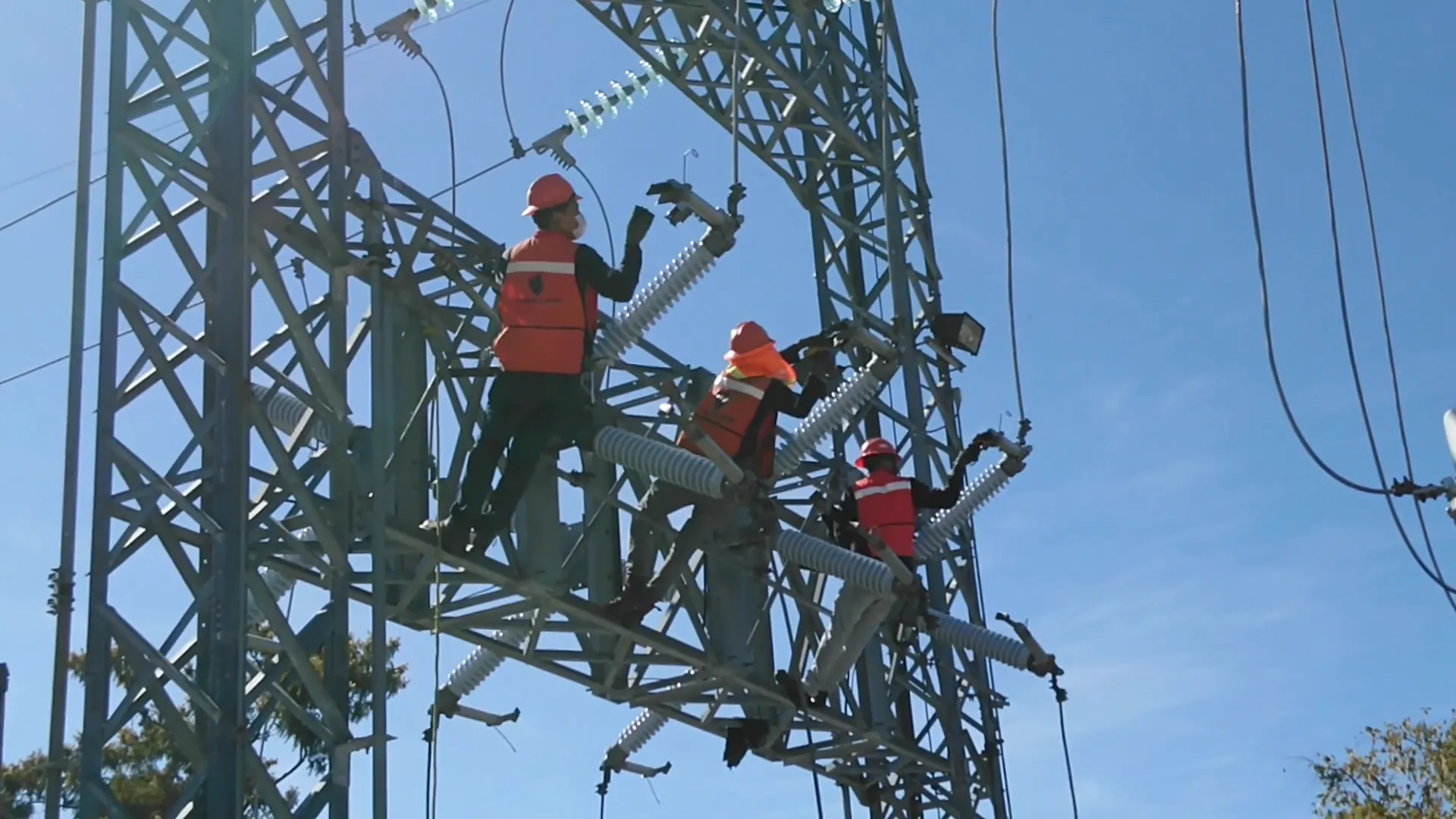 Profecionales en sistemas eléctricossobre una torre de alta tensión revisando posibles fallas